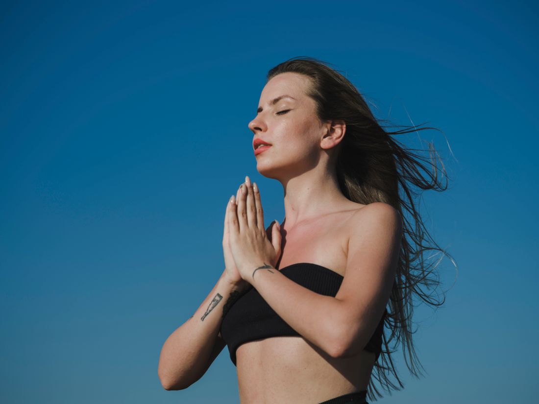 Mujer respirando profundamente con el cielo de fondo