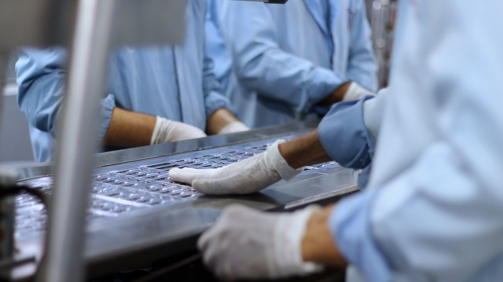 Personal empacando tabletas en planta farmacéutica