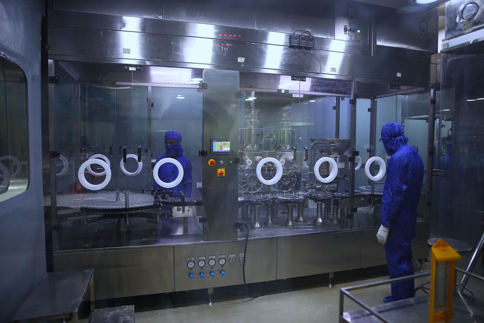 Personal con equipo de protección en área estéril de producción farmacéutica