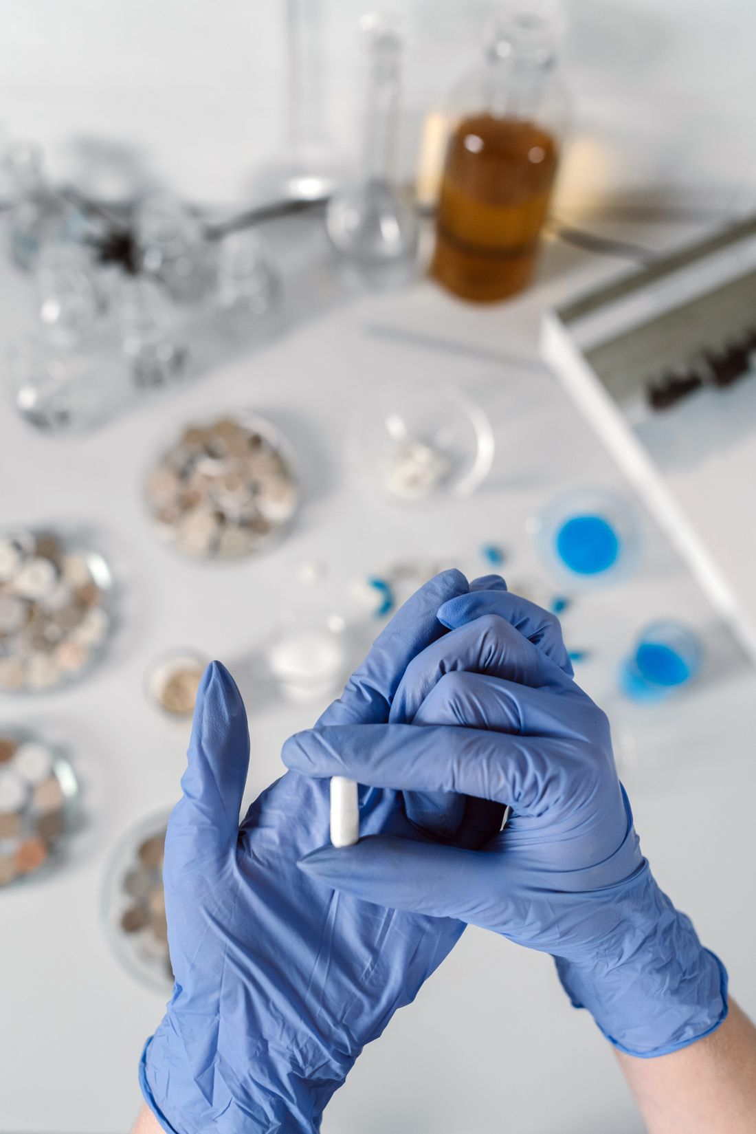 Manos con guantes sosteniendo una cápsula en el laboratorio